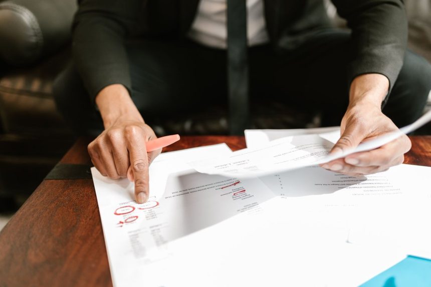 Empresário analisa documentos financeiros sobre uma mesa em um ambiente de escritório.