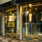 Interior de uma loja de moda masculina em São Paulo, com manequins e peças expostas na vitrine.