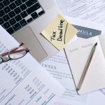 Mesa de trabalho com laptop, documentos e anotação sobre prazo fiscal, representando a gestão de obrigações tributárias.