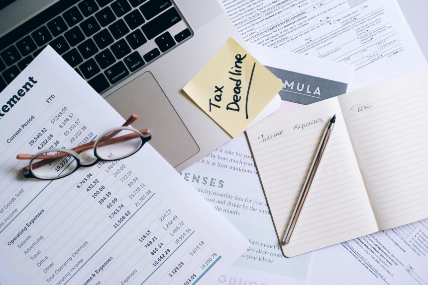 Mesa de trabalho com laptop, documentos e anotação sobre prazo fiscal, representando a gestão de obrigações tributárias.