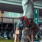 Prestador de serviços usando escada e ferramentas para realizar manutenção em uma área externa.
